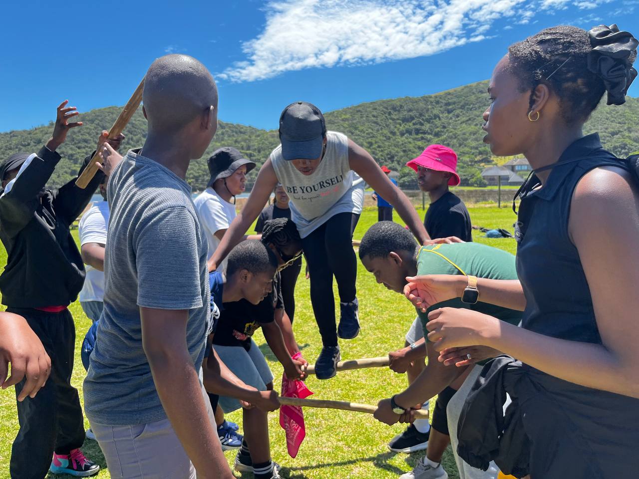 Participants supporting a teammate during an outdoor trust activity